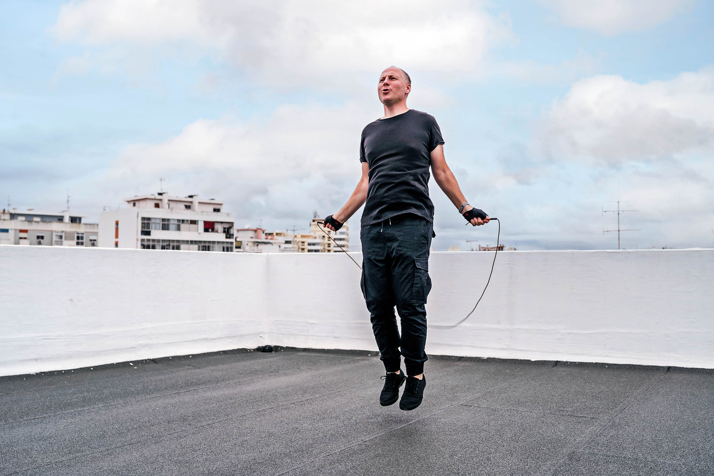 Put the Pep Back in Your Step Man on a rooftop exercising with a jump rope