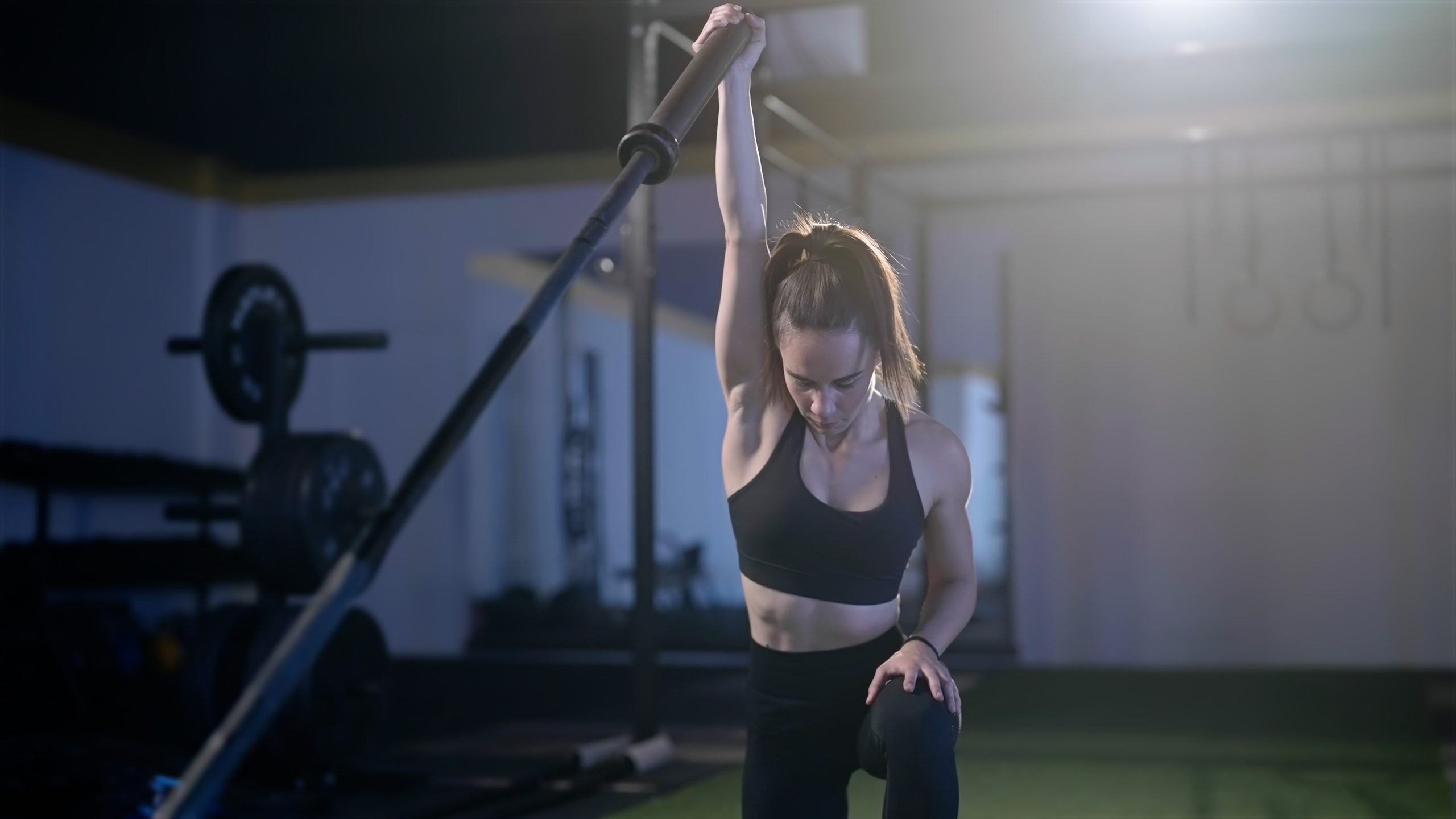 Fitness woman exercise landmine press with barbell while kneel Functional fitness landmine overhead barbell press