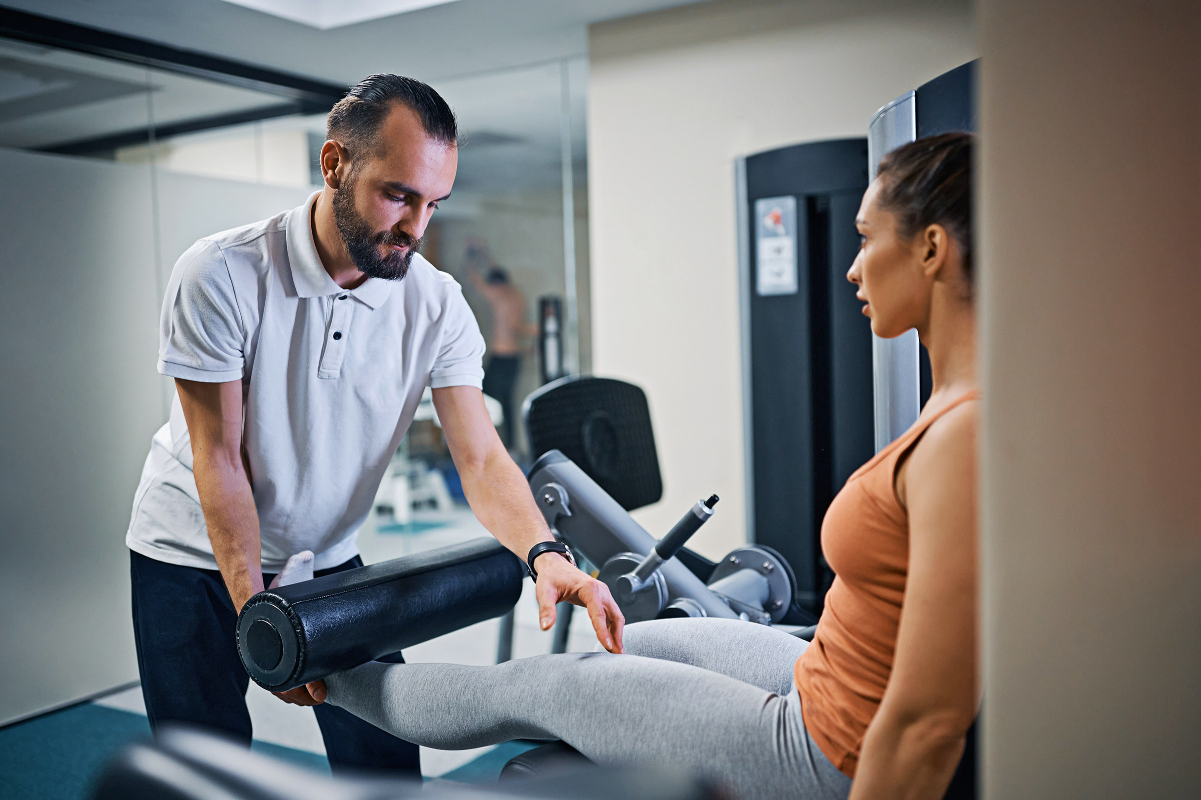 Physical therapist assists young woman with exercises on leg extension machine. Dip Exercises