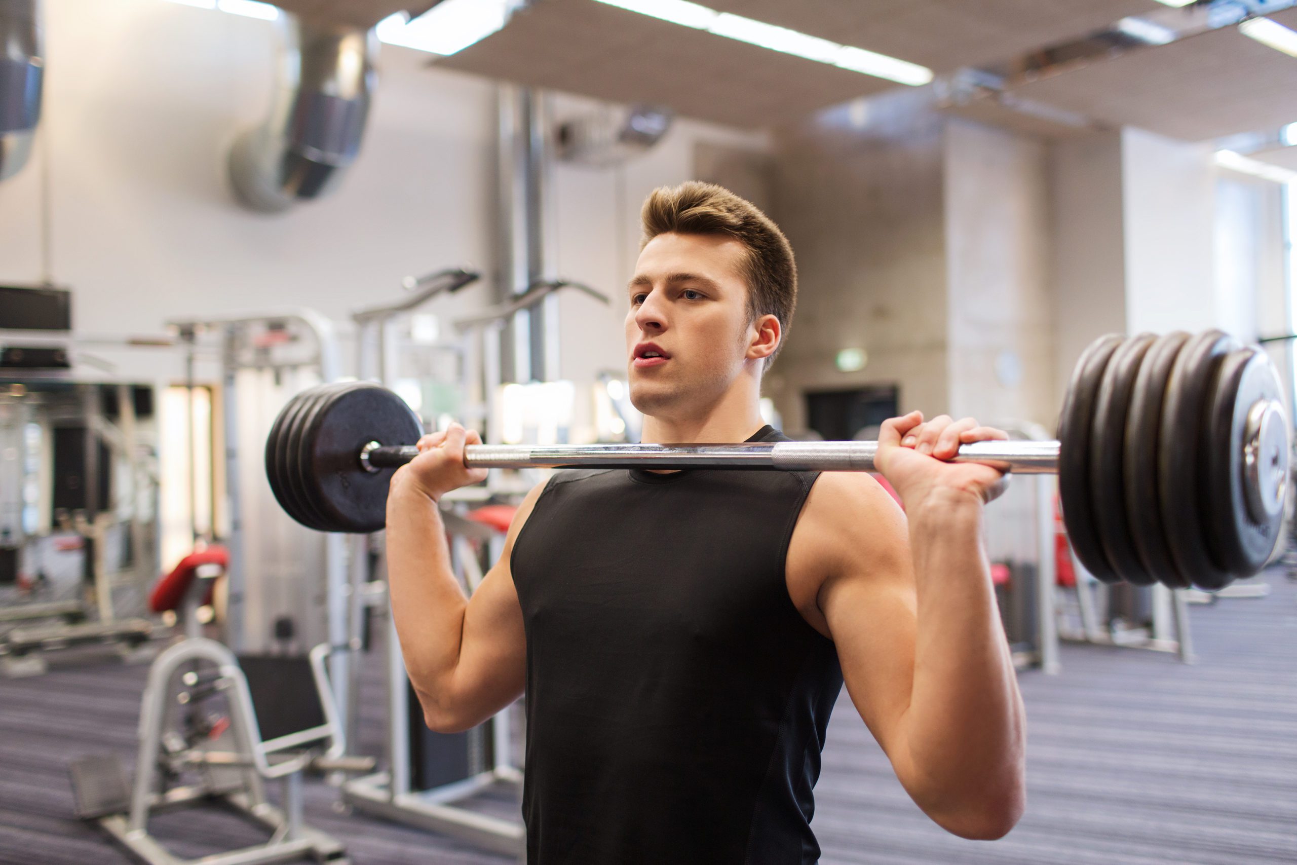young man flexing muscles with barbell in gym header image young man flexing muscles with barbell in gym header image