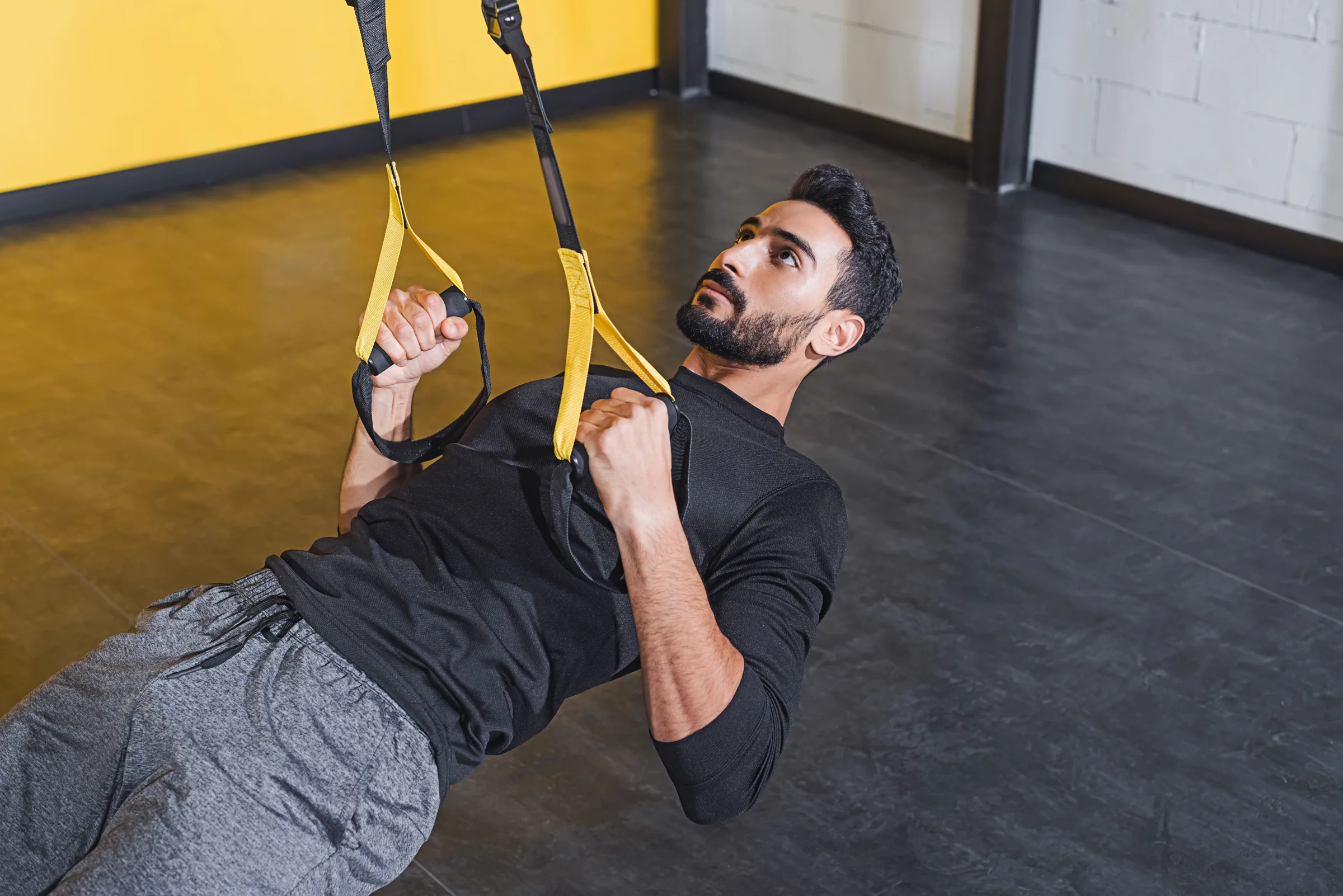 Maintaining & Making Gains During Ramdan Muslim athlete in gym using TRX bands for workout during Ramadan