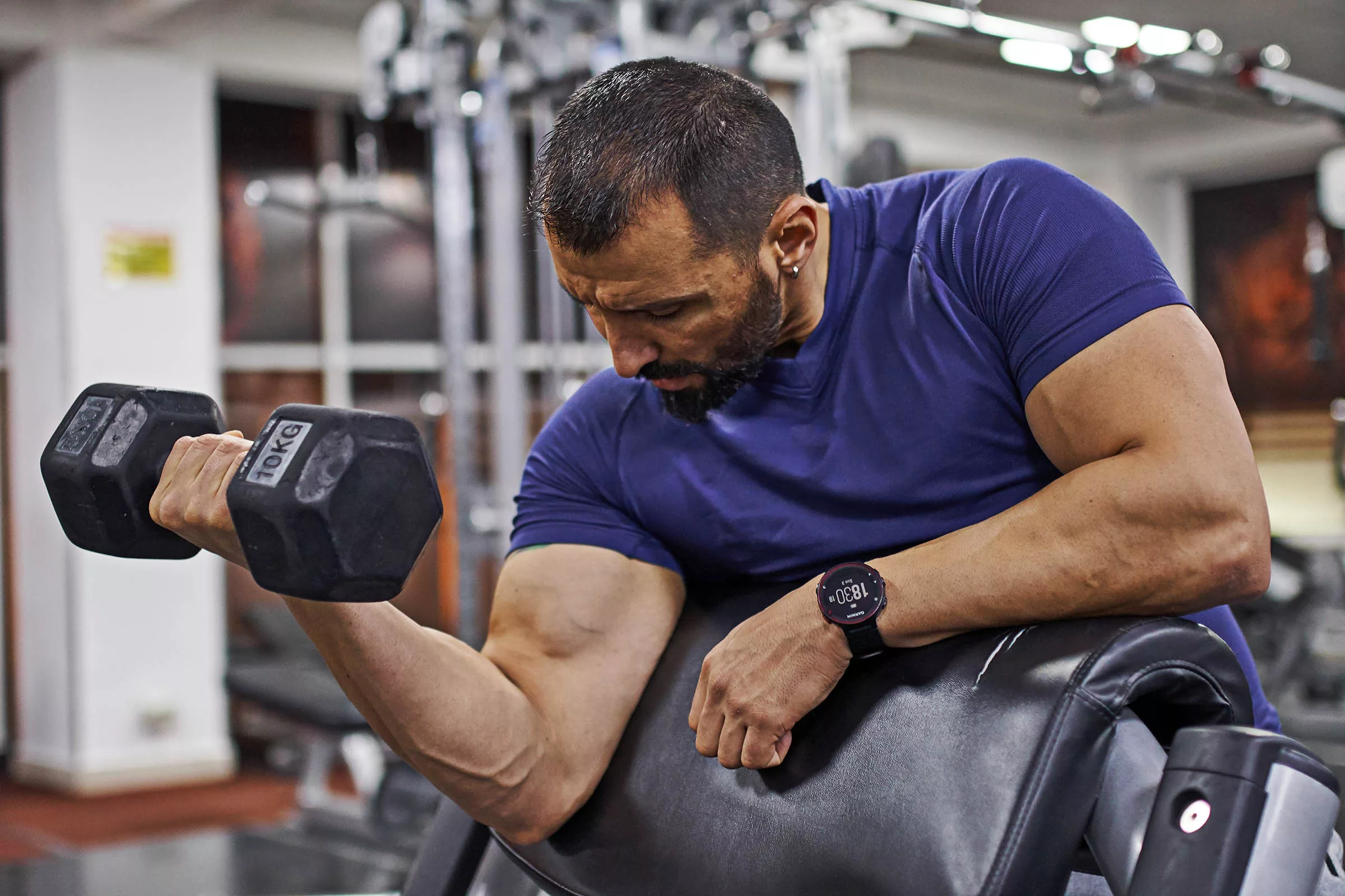 Preacher Curls for Bigger Biceps Man doing single-arm dumbbell preacher curl in gym for bigger biceps.