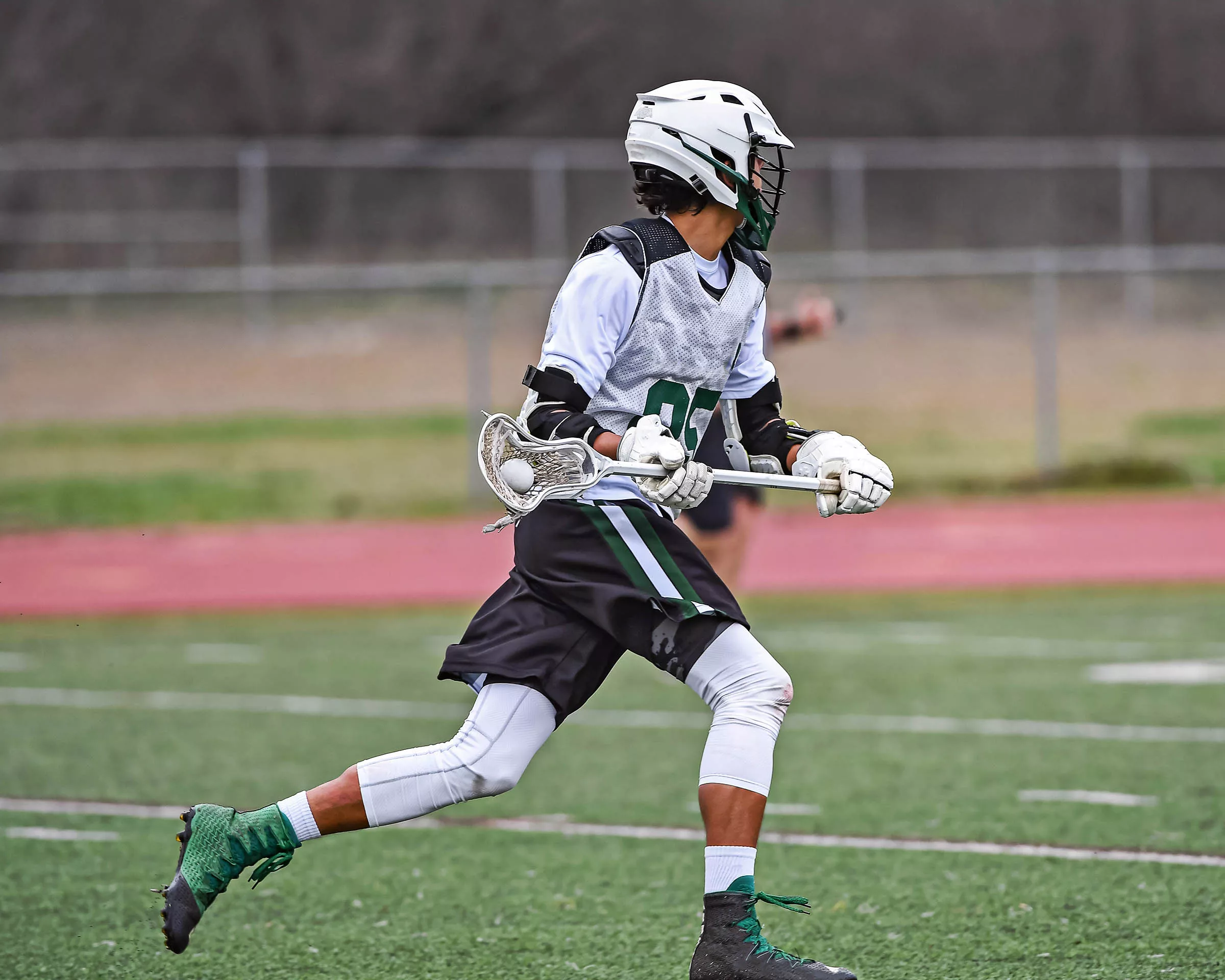 5 Exercises Every Lacrosse Athlete Should Do Athlete doing lacrosse exercise on field in full uniform