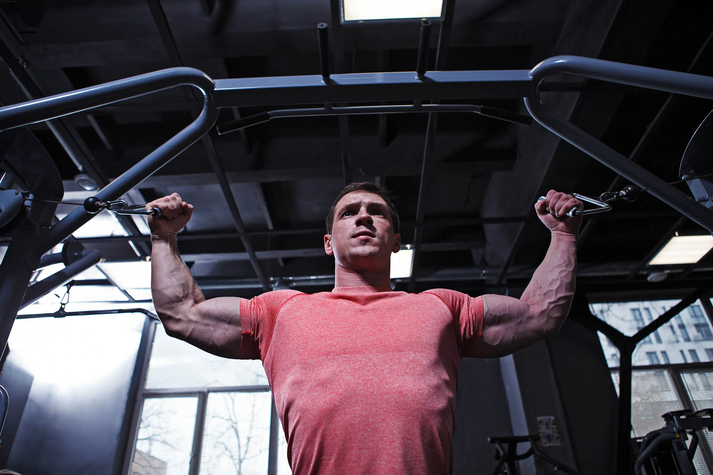 Low angle shot of a muscular strong man doing biceps workout in high cable bicep curls arm workouts for bodybuilding athletes