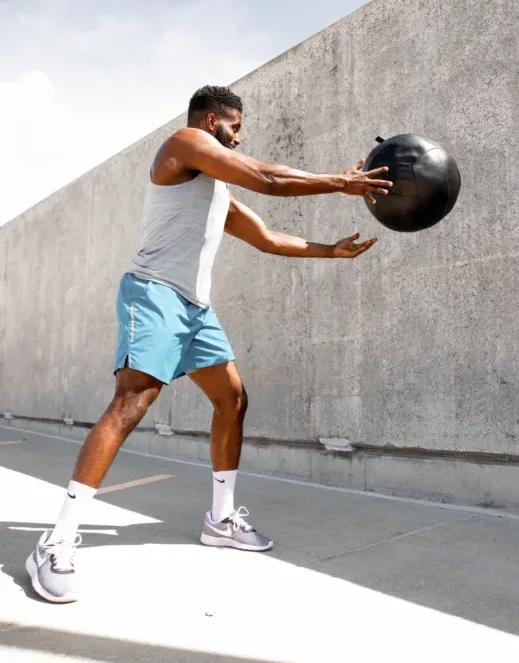 austin-wilcox-HCeifKAhHNE-unsplash A man throwing a medicine ball against.